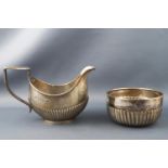 A silver half fluted decorated milk jug and sugar bowl (not a pair), the jug Birmingham 1909,