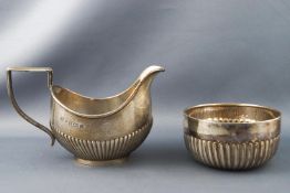 A silver half fluted decorated milk jug and sugar bowl (not a pair), the jug Birmingham 1909,