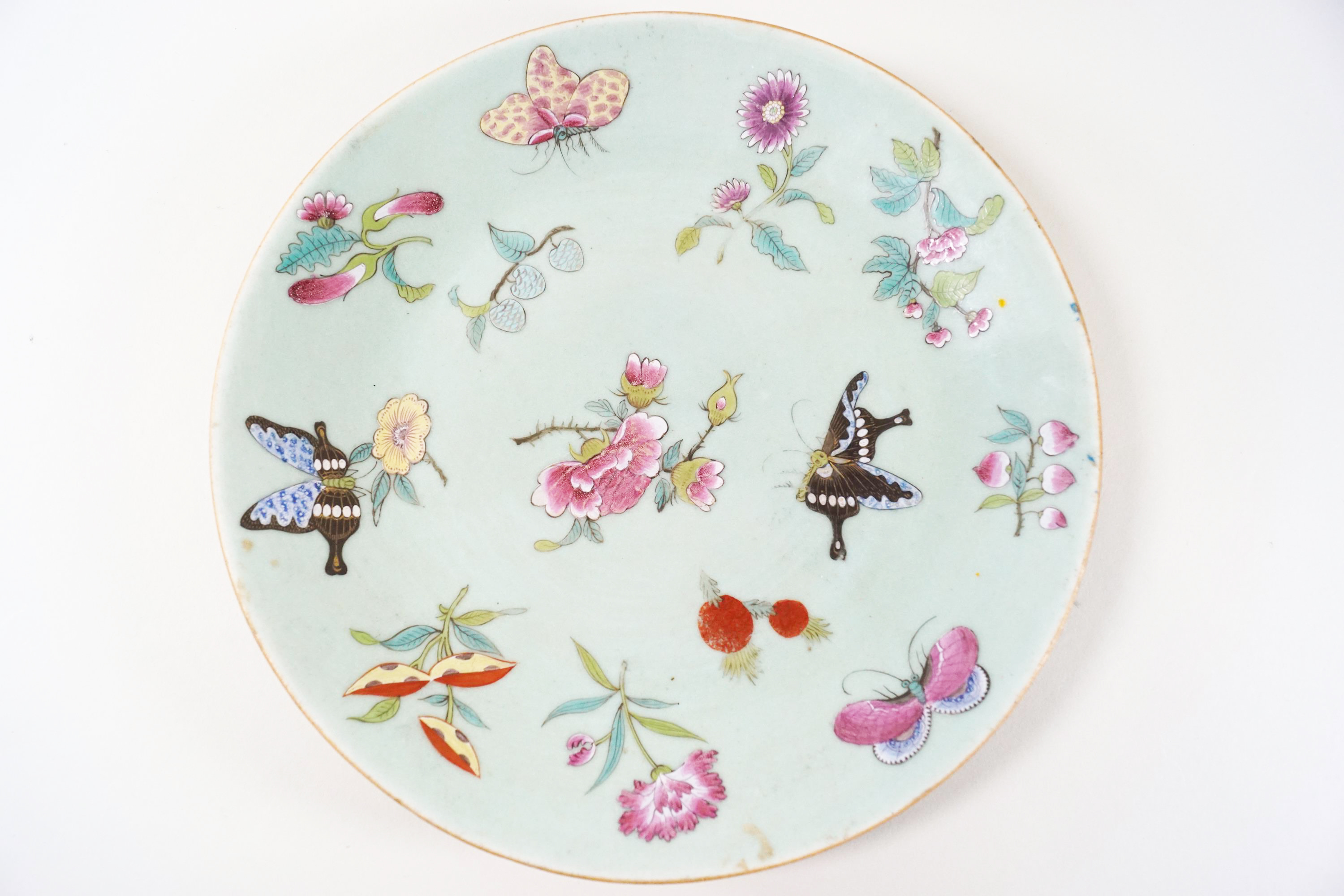 A 19th century green Chinese celadon plate, painted in Canton enamels with flowers and butterflies,