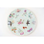 A 19th century green Chinese celadon plate, painted in Canton enamels with flowers and butterflies,