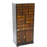An Oriental hardwood cabinet with three tiers of twenty drawers over a two door cupboard,