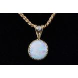 A handmade yellow metal pendant set with a shallow cabochon opal and a single diamond.