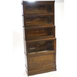 A five section Globe Wernicke bookcase, the bottom section with solid drop door raised on a plinth,