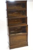 A five section Globe Wernicke bookcase, the bottom section with solid drop door raised on a plinth,