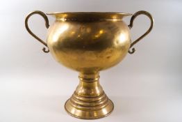 A large scale brass two handled urn with flared foot.