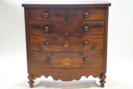 A mahogany bow front chest of two short and three long drawers over a shaped apron on baluster