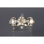 A white metal diamond ring set with three graduated round brilliant cut diamonds,