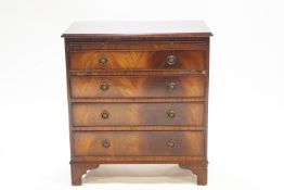 A mahogany veneered dressing chest of four drawers, with a brushing slide on raised bracket feet,