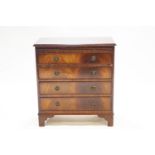 A mahogany veneered dressing chest of four drawers, with a brushing slide on raised bracket feet,