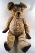 A large plush covered teddy bear, with replacement leather pads to his paws,