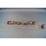 A selection of amber jewellery consisting of three pendant and chains, one bracelet,