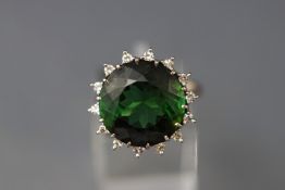 A white metal cluster ring set with a round faceted green tourmaline approx 14.