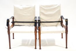 A pair of teak campaign chairs with canvas backs and seats,