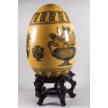 A large ceramic decorative egg with scenes of fruit in urns,