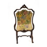 A 19th century walnut fire screen of carved Rococo form,