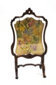 A 19th century walnut fire screen of carved Rococo form,