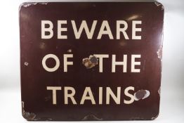 A 'Beware of the Trains' enamel sign on a brown ground,