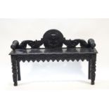 A Victorian ebonised oak window seat with carved shaped back and legs,