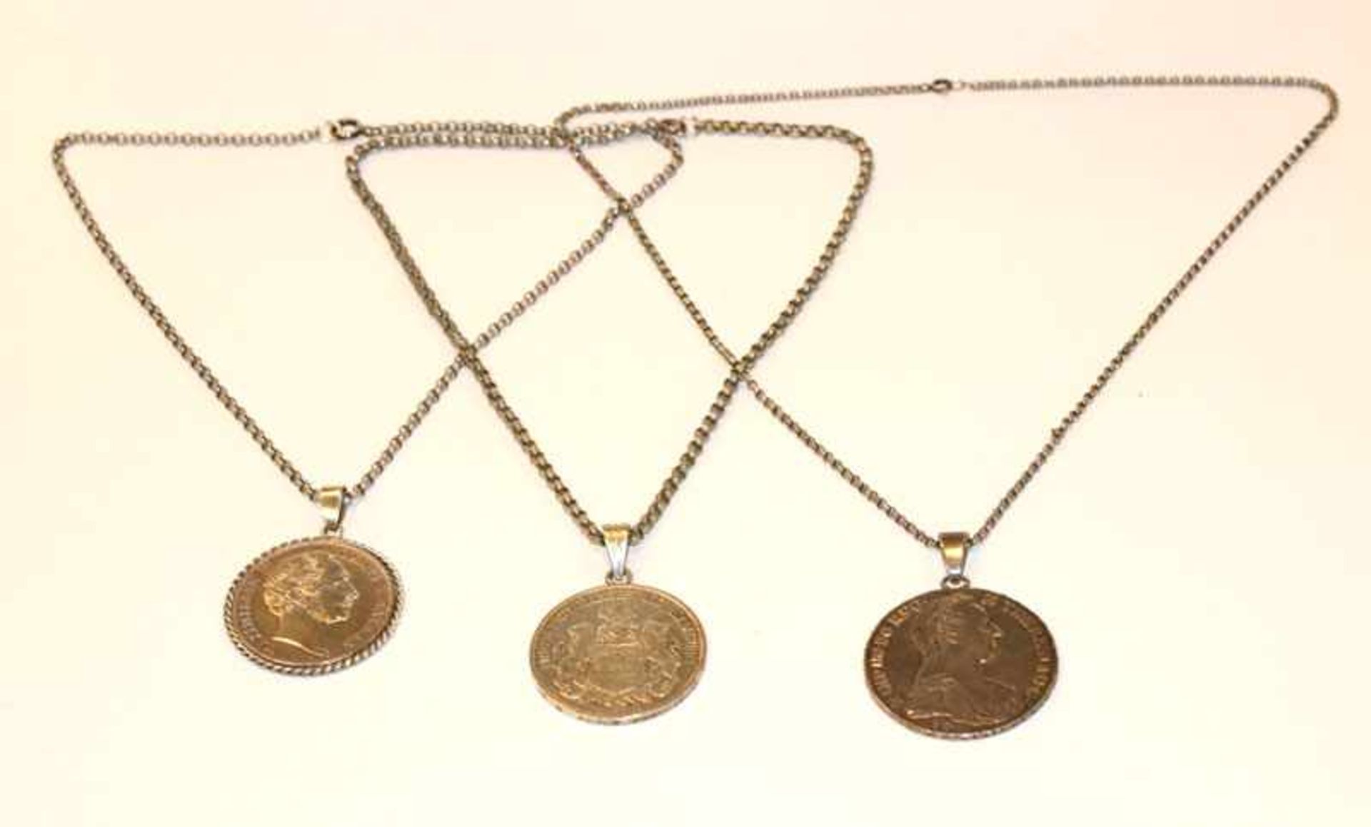 3 Silberketten, L 38, 42 und 54 cm, mit je einer gehenkelten Silbermünze, zus. 110 gr.