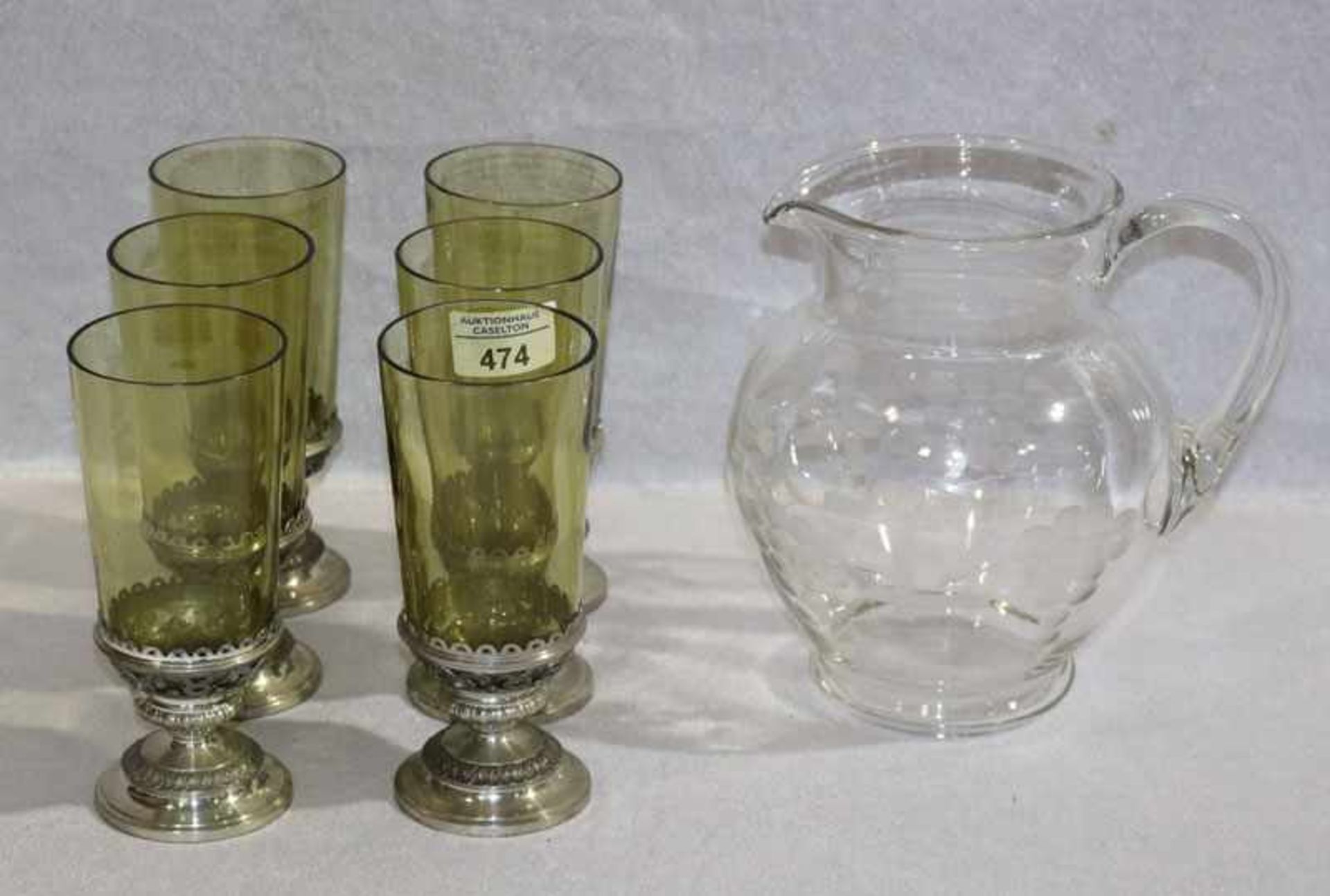 Glas Henkelkrug mit Traubendekor, H 20 cm, und 6 grüne Gläser mit Zinnfuß, H 16,5 cm,