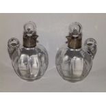 A pair of silver mounted glass oil bottles with stoppers, each having glass loop handle,