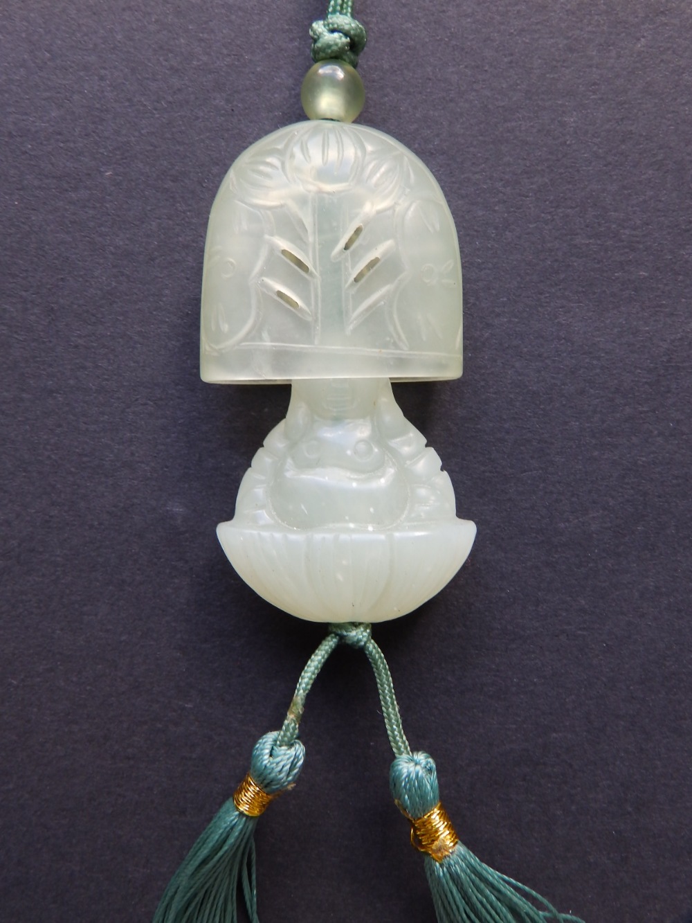 A Chinese jade concealed Buddha pendant, the flattened domed cover open carved with a flowering