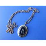 An oval black enamel locket decorated with the letter 'R' on chain.