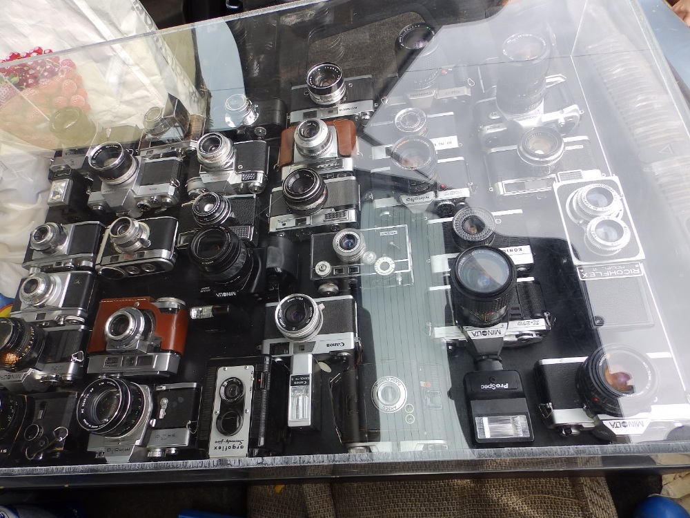 A perspex coffee table fitted with a display of late 20thC cameras.