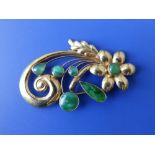 A Chinese yellow metal flower scroll brooch set with bright jade coloured stones – '14K', 2.3”.