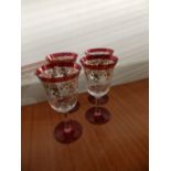 Four large ruby glass stemmed glasses with gilt decoration.