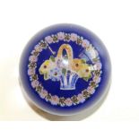 A cristallo-ceramie paperweight decorated with a basket of flowers to centre within a band of