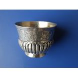 A small unmarked antique white metal wine cup, having a frieze of arabesque leaf scroll engraving