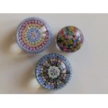 A small millefiori flowerhead paperweight, 2.5” diameter, and two other small millefiori weights. (