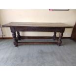 An antique refectory table with lunette carved frieze, standing on turned legs united by low