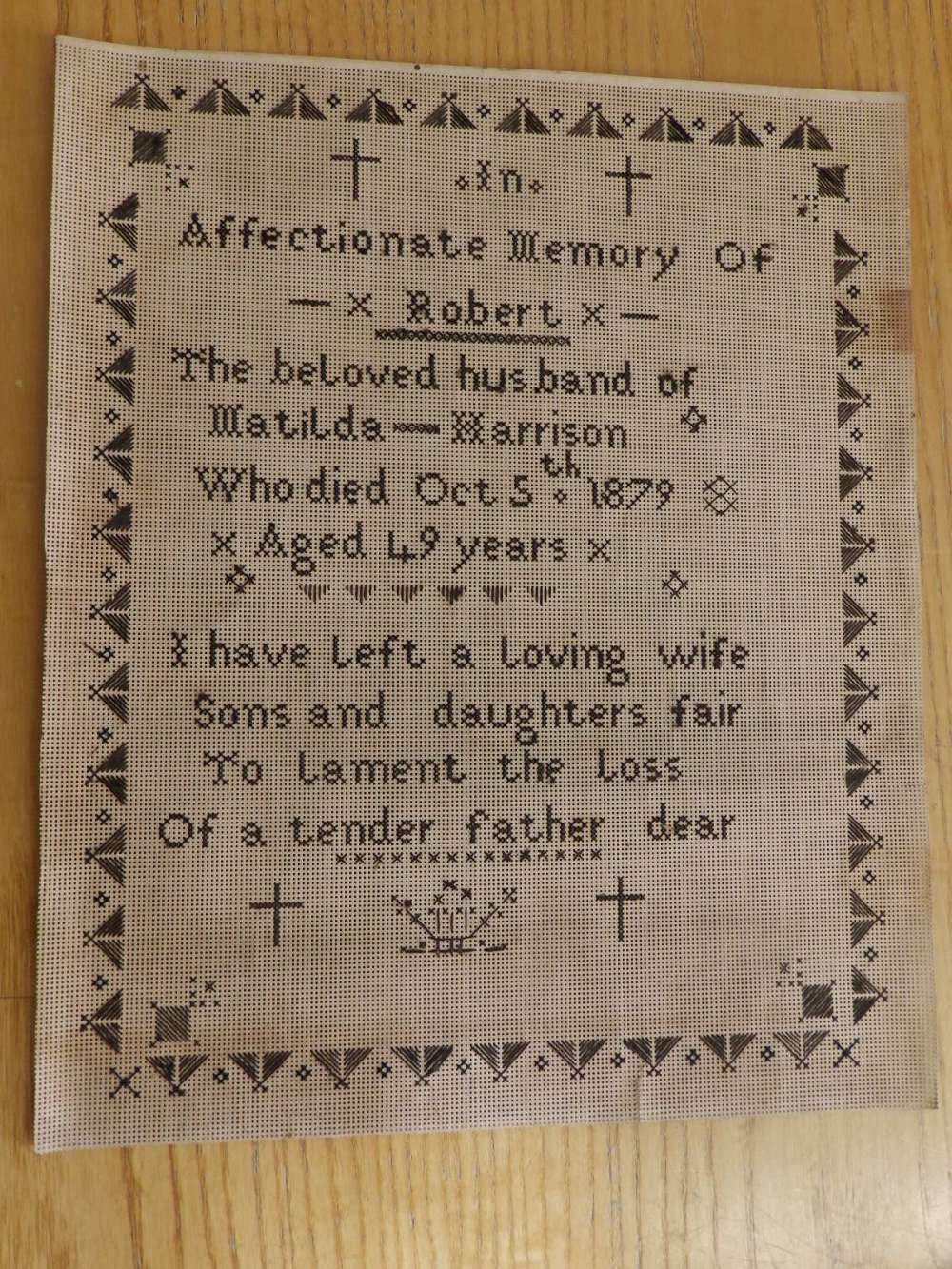 A black thread sampler worked on perforated card ground – 'In affectionate memory of Robert