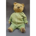 A mid-20th century wood wool filled teddy bear having green coloured knitted outfit