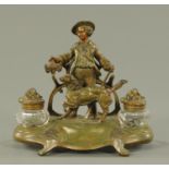 A late 19th/early 20th century spelter ink stand, two inkwells and with huntsman with dog between.