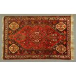 An Eastern fringed rug, principal colours red, orange and beige. 173 cm x 118 cm.