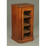 A Regency mahogany music cabinet, shaped outline, with single door with brass grille,