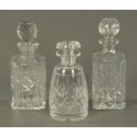 Two cut glass spirit decanters, and a cylindrical decanter.