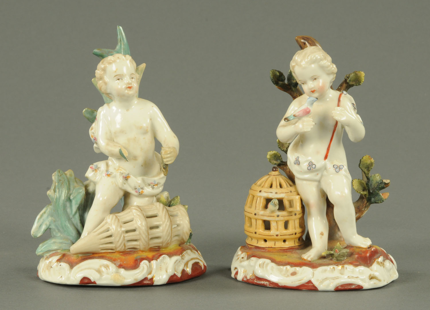 Two German putto figures, each with cage. Height 15 cm.
