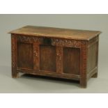 An 18th century carved oak three panelled coffer, with iron lock and interior lidded compartment,