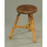 A 19th century elm cricket stool, with circular top and three legs united by stretchers.