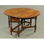 A George III oak twin drop flap oval dining table, with turned supports,