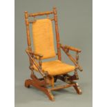 A late Victorian child's American rocking chair, typical form, with upholstered back and seat.