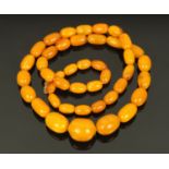 A string of butterscotch amber beads, of graduating olive shape, smallest 16 mm wide,