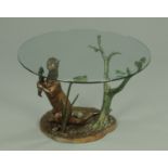 A glass topped coffee table, raised on a bronze base modelled as an otter with fish.