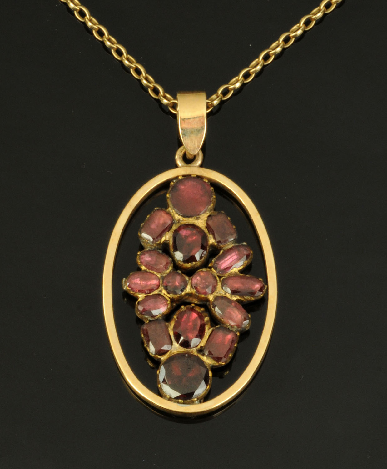 A garnet set oval pendant, in gold coloured metal mount suspended on a 9 ct gold fine link chain.