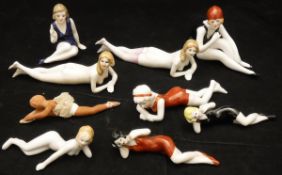 A collection of nine circa 1920 biscuit fired porcelain pin cushion type dolls,