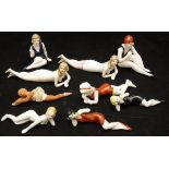 A collection of nine circa 1920 biscuit fired porcelain pin cushion type dolls,